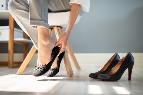 Frau mit Fußschmerzen durch enge Schuhe